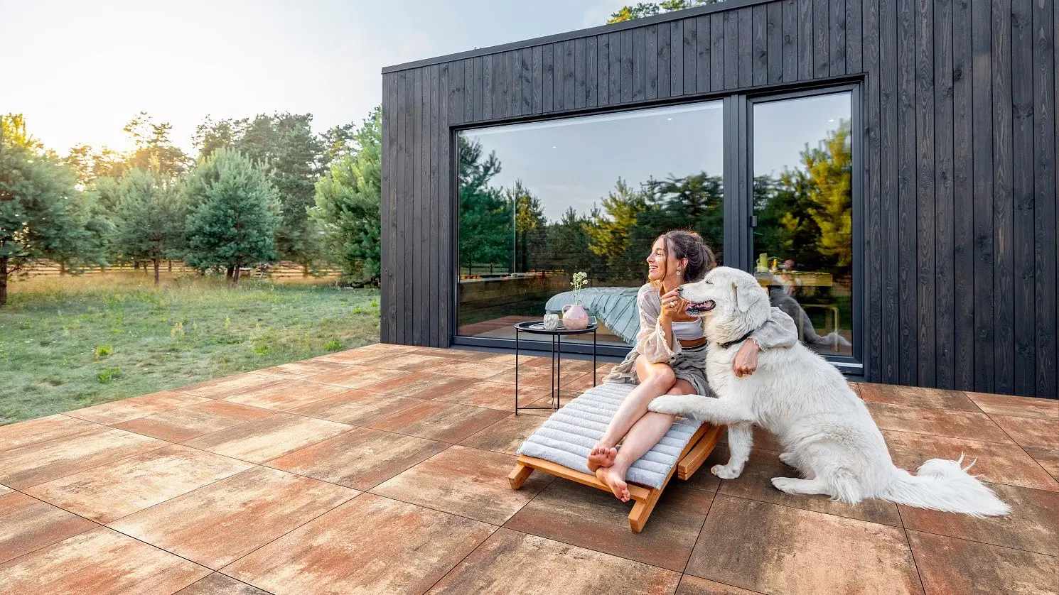 Gestaltete Terrasse mit warmen Terrassenplatten vor einem modernen Haus
